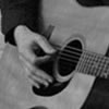 Man with glasses and hat poses with guitar