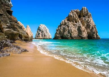 A beach in Cancun with a roc arch in the water.